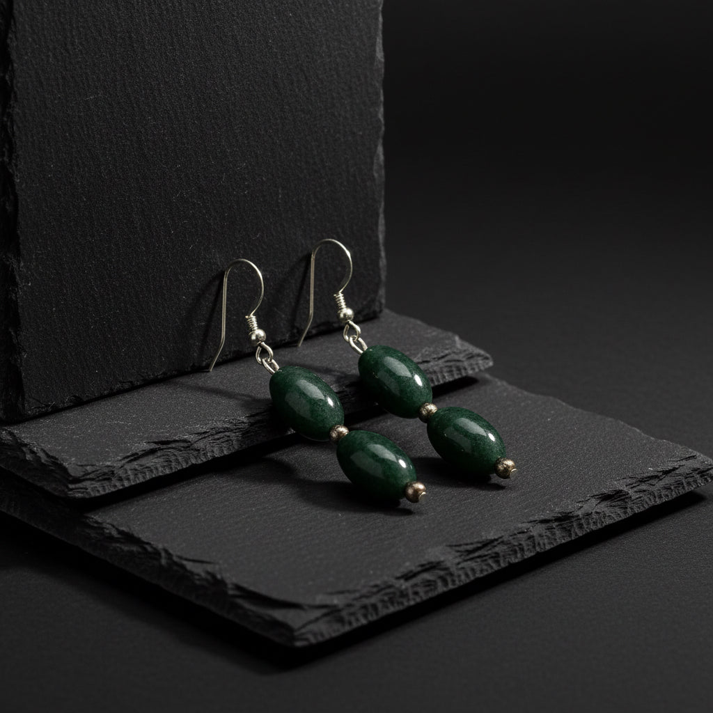 A pair of dangling earrings featuring polished dark green stone beads, separated by small metallic spacer beads, hanging from silver-toned fishhook wires on a plain white background.