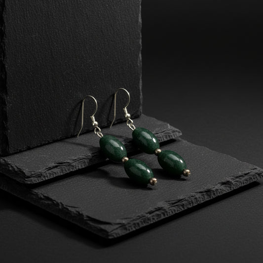 A pair of dangling earrings featuring polished dark green stone beads, separated by small metallic spacer beads, hanging from silver-toned fishhook wires on a plain white background.