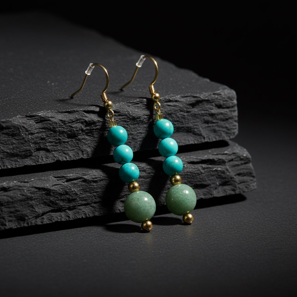 A pair of gold-tone dangle earrings featuring four stacked turquoise beads and a larger textured green stone bead at the bottom, set against a plain white background.