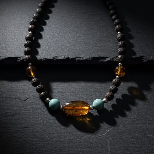 A handmade beaded necklace featuring dark brown lava stones, translucent amber beads, and light blue turquoise beads, displayed on a weathered gray wooden surface. A watermark for 'luki lapidary' is visible in the bottom right corner.