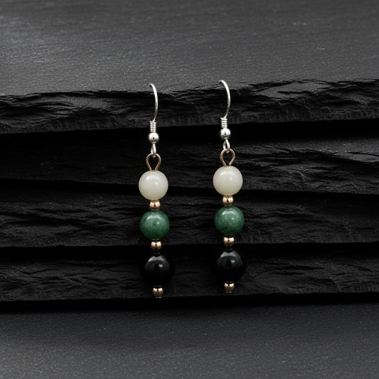 A pair of dangle earrings with three stacked round beads on each earring. The beads are white, green, and black, separated by small rose gold spacer beads, hanging from silver fishhook wires on a plain white background.