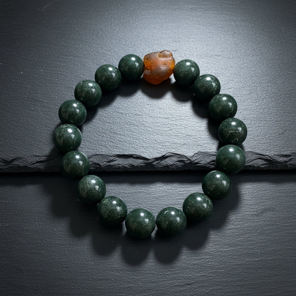 A beaded stretch bracelet made of glossy dark gray to black round beads, with one larger irregular brown stone bead at the top, displayed on a weathered gray wood surface.