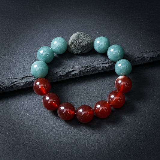A beaded bracelet made of round polished stones, featuring teal-blue beads on one side, reddish-brown carnelian-like beads on the other, and a dark gray stone in the center, displayed on a weathered wood surface.